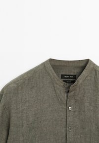 Olijfgroene linnen shirt met ronde kraag en drie zichtbare knopen, met het merklabel Massimo Dutti zichtbaar binnenin de hals.