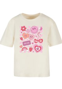 Cream cotton t-shirt featuring a colorful graphic design of hearts, flowers, and playful elements in pink, with a relaxed fit and rounded neckline.