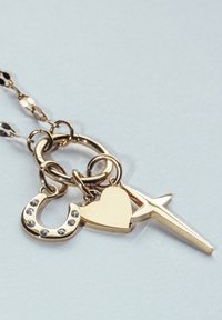 Goldene Kettenhalskette mit drei Anhängern: einem Hufeisen, das mit kleinen Kristallen verziert ist, einem glatten Herzen und einem schlanken Kreuz.