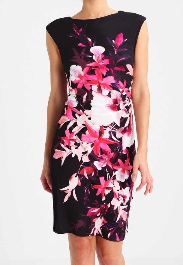 Robe noire sans manches avec imprimé floral rose vif et blanc, coupe ajustée, portée par une personne debout, les bras détendus le long du corps.