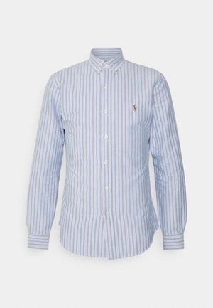 Vaaleansinivalkoraidallinen nappisomisteinen pitkähiha-paita, jossa pientä kirjailtua logoa vasemmalla rinnalla.