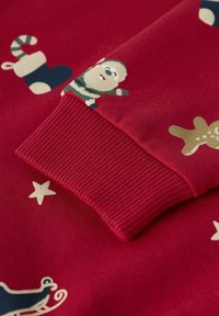 Roter Sweatshirt mit gerippten Bündchen, dekoriert mit Weihnachtsmotiven wie Santa, Lebkuchen und Sternen.