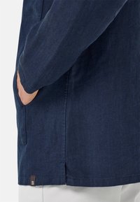 Marineblauwe hounds-tooth patroon jasje met lange mouwen, zijzak en een klein bruin label aan de zoom. Glad van textuur, getailleerde pasvorm.