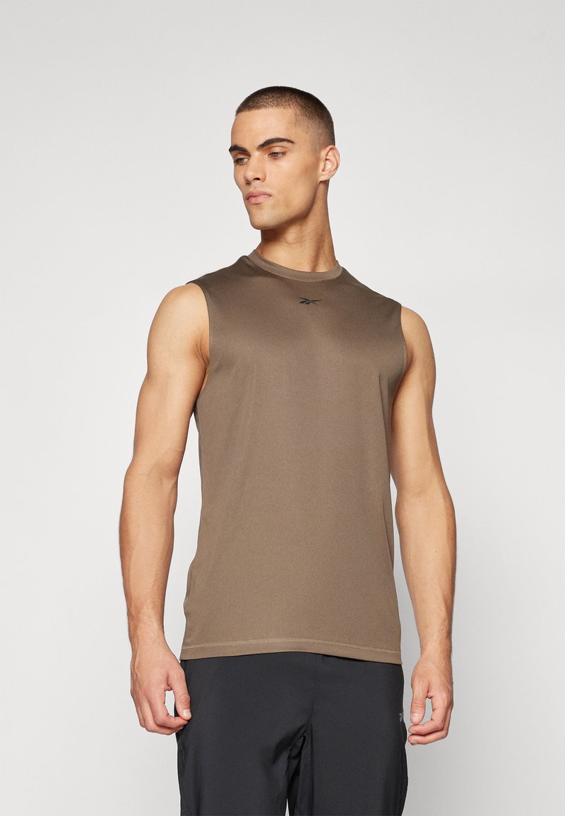 Top atlético sin mangas marrón, fabricado en un material suave, con un escote redondo y un sutil detalle de logotipo, combinado con pantalones cortos deportivos oscuros.