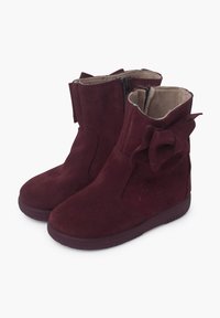 Botines de ante burdeos con cierre de cremallera, detalle de lazo en el costado y suela de goma texturizada. Interior suave forrado para mayor comodidad.