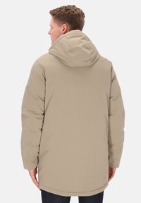 Parka beige imbottita con cappuccio, tasche laterali e esterno texturizzato, con orlo posteriore leggermente più lungo e silhouette elegante.