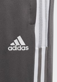 Dunkelgraue Sporthosen mit weißem Adidas-Logo, aus strukturiertem Stoff und mit drei weißen Akzentstreifen an der Seite.