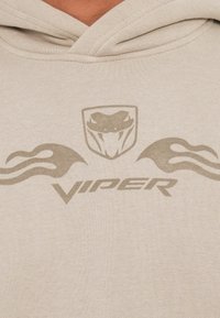 Felpa leggera color beige chiaro con logo Viper e grafica di un serpente in un beige leggermente più scuro. Il tessuto ha una texture morbida e un cappuccio regolabile con cordino.