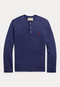 Marinblå långärmad henley-tröja i mjukt bomull. Har en treknappad knappslå och en liten broderad röd logotyp på vänster bröst.