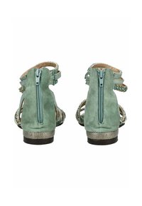 Grüne Wildleder-Sandalen mit Rückenzipper, dekorativen Riemen und einem strukturierten, metallischen Absatz. Offenes Design und verzierte Akzente sind vorhanden.