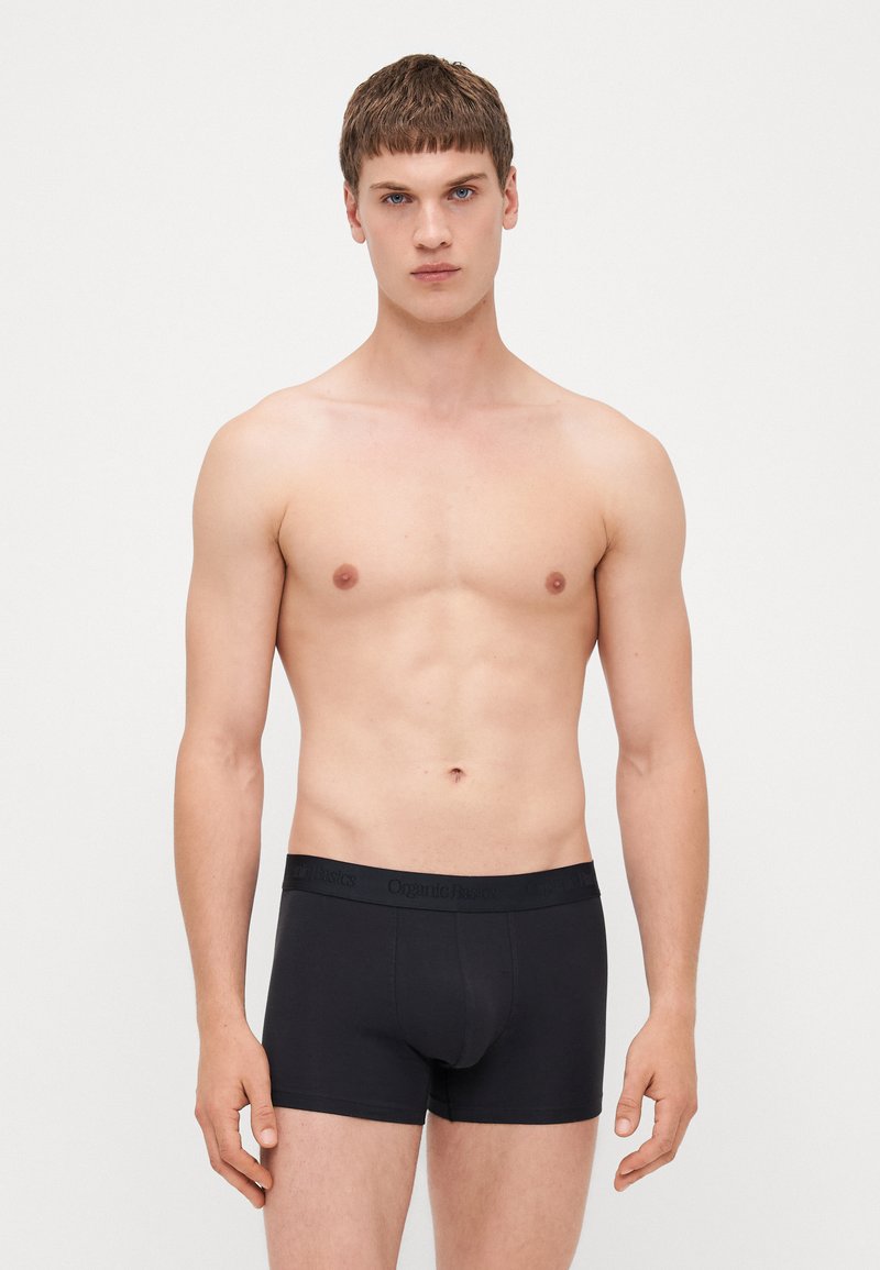 Schwarze Boxershorts aus Bio-Baumwolle mit einem weichen Bündchen, das die Marke "Organic Basics" trägt, einer körpernahen Passform und glatter Textur.