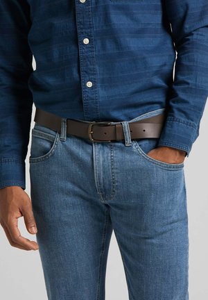 Chemise bleu foncé à boutons avec des rayures horizontales discrètes, associée à un jean bleu clair et une ceinture en cuir marron avec une boucle en métal.