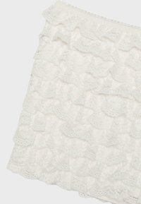 Jupe en dentelle blanche avec des volants superposés présentant des motifs floraux, conçue pour un style féminin et élégant.