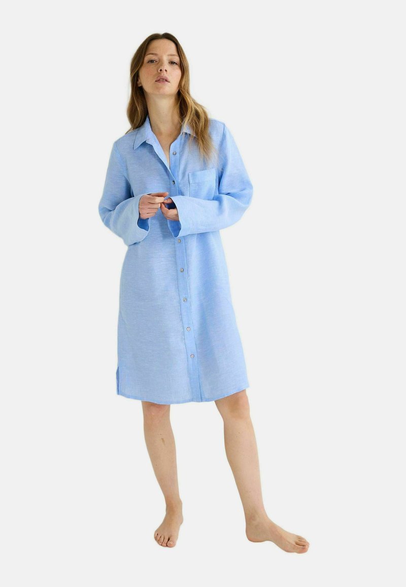 Robe chemise en lin bleu clair avec un devant à boutons, des manches longues et une poche poitrine ; coupe décontractée avec des fentes latérales à l'ourlet.