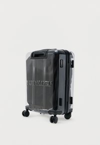 Maleta rígida negra brillante con capa exterior transparente, cuatro ruedas giratorias y "FOR TRAVEL" grabado en el frente.