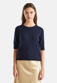 Granatowy sweter z krótkim rękawem o okrągłym dekolcie, wykonany z miękkiego materiału, z luźnym krojem i ściągaczami przy rękawach.