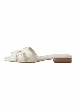 White leather flat slide sandal with two wide overlapping straps and a low stacked wooden heel, shown from the side on a white background.