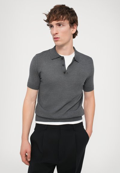 Kortærmet grå polo-shirt med to-knap lukning, struktureret stof og ribbet kant, parret med skræddersyede sorte bukser.