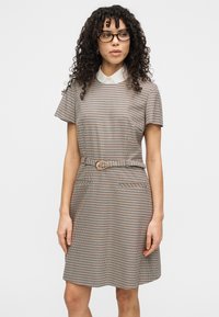 Καφέ και κρεμ φόρεμα με μοτίβο χακι, κοντά μανίκια, γιακά, ζώνη στη μέση και δύο μπροστινές τσέπες. Ομαλή υφή υφάσματος.