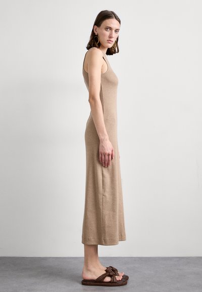 Vestito aderente senza maniche, lunghezza fino a metà polpaccio, texture a coste. Abbinato a sandali intrecciati marroni. Sfondo neutro.