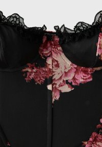Haut de lingerie en résille noire avec imprimé floral rose et bordure en dentelle noire le long du décolleté.