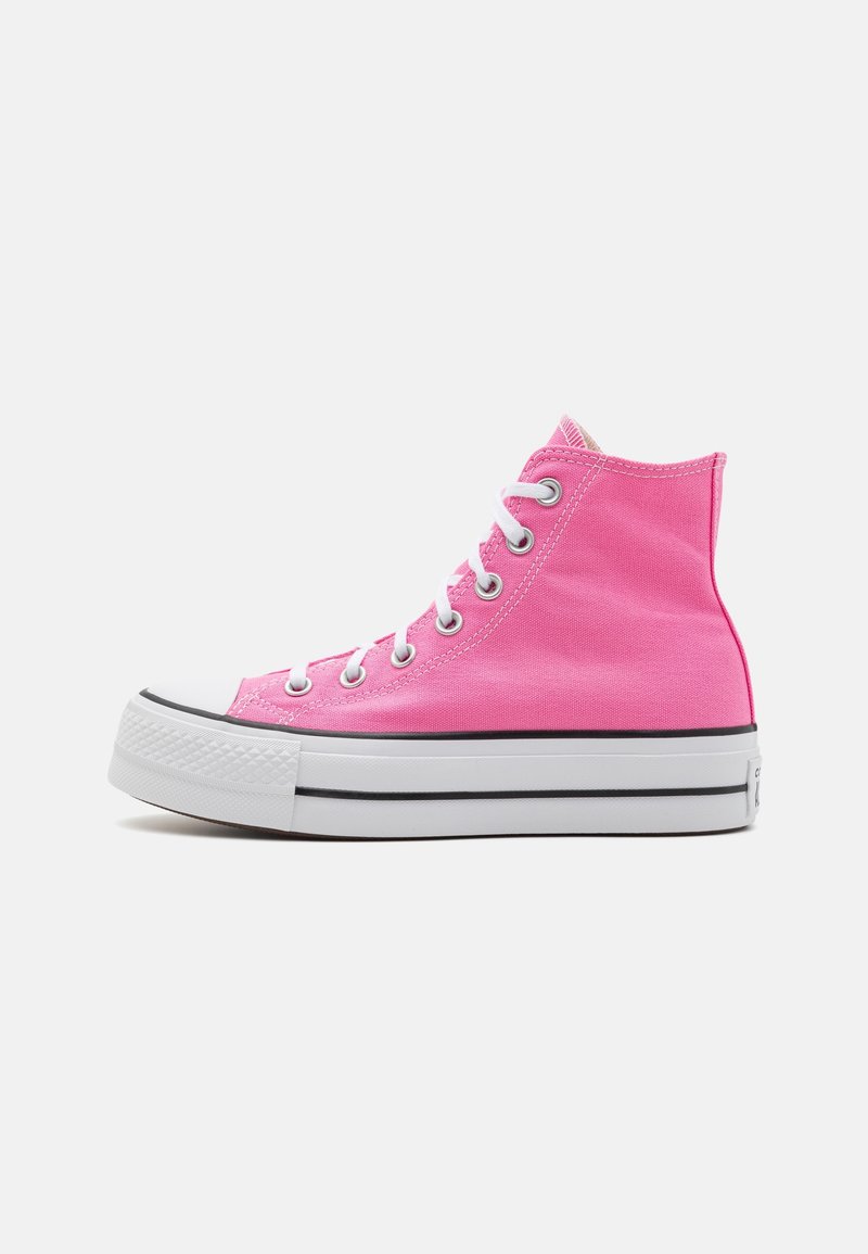 Sneakers montantes en toile rose avec lacets blancs et semelle épaisse en caoutchouc blanc avec des détails à bandes noires.