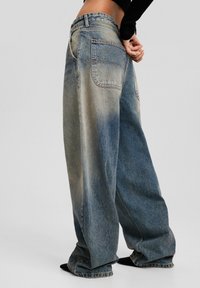 Bredbeniga blå denimjeans med en urtvättad yta, som har två bakfickor och hög midja. Byxorna har en avslappnad passform och snygg sömnad.