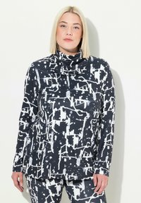 Tunic a motivo bianco e nero con collo a cowl, caratterizzata da design astratti di spruzzi e maniche lunghe, realizzata in un tessuto morbido e elasticizzato.