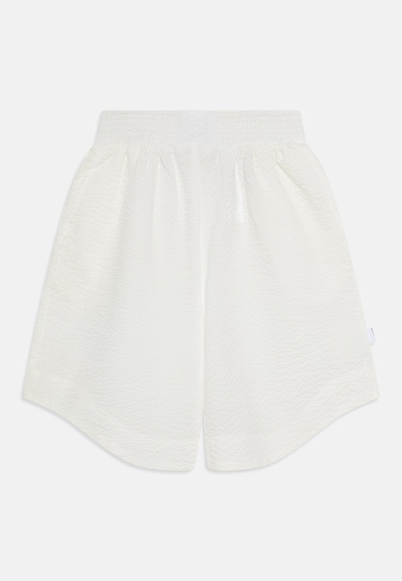 Shorts blancs en tissu texturé avec une taille élastique, présentant une coupe ample et des ourlets arrondis pour le confort et la liberté de mouvement.