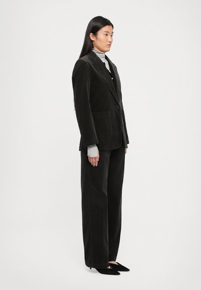 Dark green corduroy blazer with notch lapels and front pockets, paired with matching wide-leg trousers and pointed black heels.