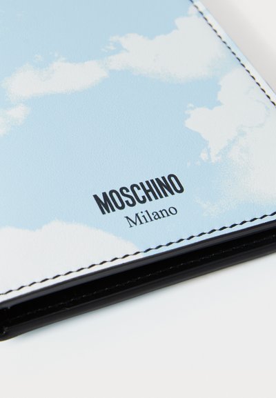 Notebook Moschino con copertina testurizzata di colore azzurro chiaro, caratterizzata da un motivo a nuvole e con il logo stampato in nero "Moschino Milano" in basso.