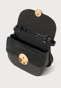 Borsa nera con design testurizzato a coccodrillo, pattina in suede, hardware dorato e interno con zip. Si apre con un gancio circolare.