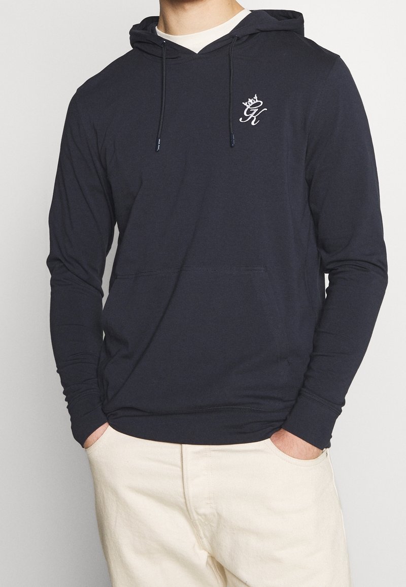 Námořnická bavlněná mikina s přední kapsou, kapucí na šňůrku a vyšívaným logem na hrudi. Dlouhé rukávy s žebrovanými manžetami.