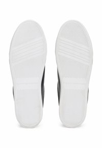 Schwarze Sneaker-Sohlen mit weißen Gummi-Außensohlen. Verfügt über horizontale Rillen für besseren Halt und ein eingeprägtes Markenlogo. Glatte Oberfläche.