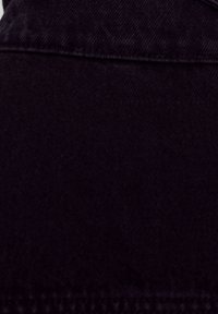 Black denim fabric with a smooth texture, featuring a subtle sheen and stitched seams. The material is durable and slightly stretchy.