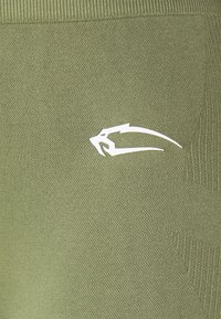 Tejido de punto verde oliva con un patrón texturizado; presenta un logotipo blanco en el costado. Incluye acentos de canalé en la parte superior.