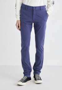 Pantaloni din bumbac mov, cu o croială slim, având buzunare frontale, închidere cu buton și teniși negri cu accente albe.