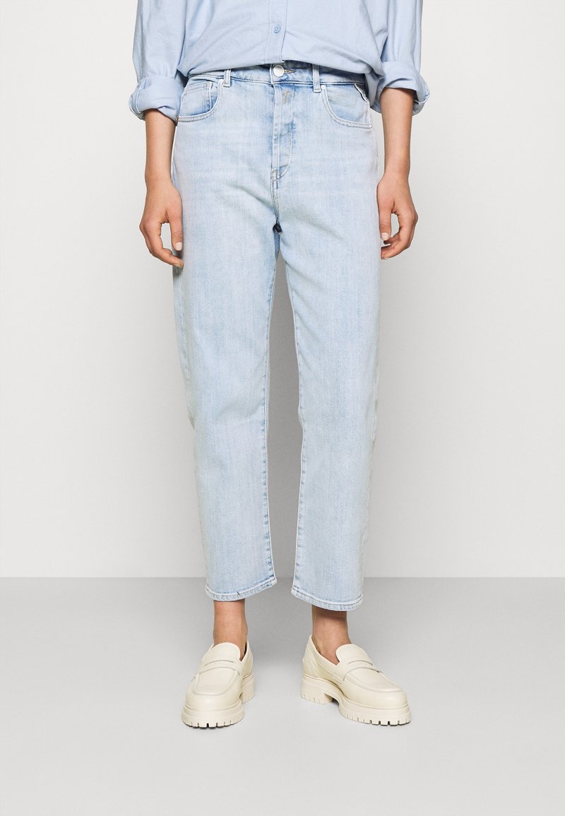 Jasnoniebieskie dżinsy z prostą nogawką, z pięcioma kieszeniami i wyblakłą fakturą, zestawione z kremowymi butami wsuwanymi.
