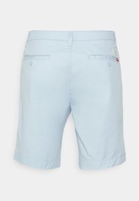 Shorts pour hommes bleu clair avec deux poches arrière passepoilées à bouton, des passants de ceinture et une petite étiquette de marque rouge sur la poche droite.