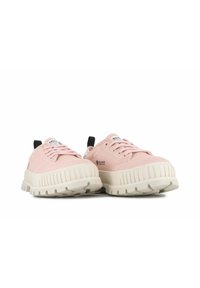 Zapatillas de lona rosas con una suela de goma blanca gruesa, que presentan un patrón texturizado en la suela y acentos negros en el talón y la lengua.