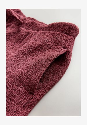 Textured, deep burgundy fabric with a fuzzy surface, featuring a rolled edge and an angled cut at the hem. Ideal for casual garments.