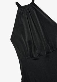 Musta kaula-aukkoinen mekko, jossa on taitettu yläosa, sileä kangas ja vartalonmyötäinen siluetti. Materiaali on hienovaraisesti kimalteleva.