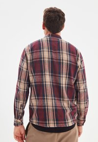 Camicia a maniche lunghe a quadri rossi, beige e blu navy, con texture morbida, polsini con bottoni e orlo curvo.