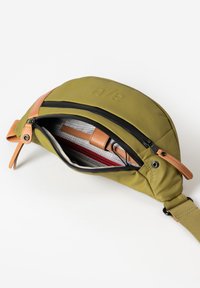 Olijfgroene tas met een gladde textuur, leren accenten en een rits aan de voorkant. Het interieur heeft een rode en grijze voering met compartimenten.