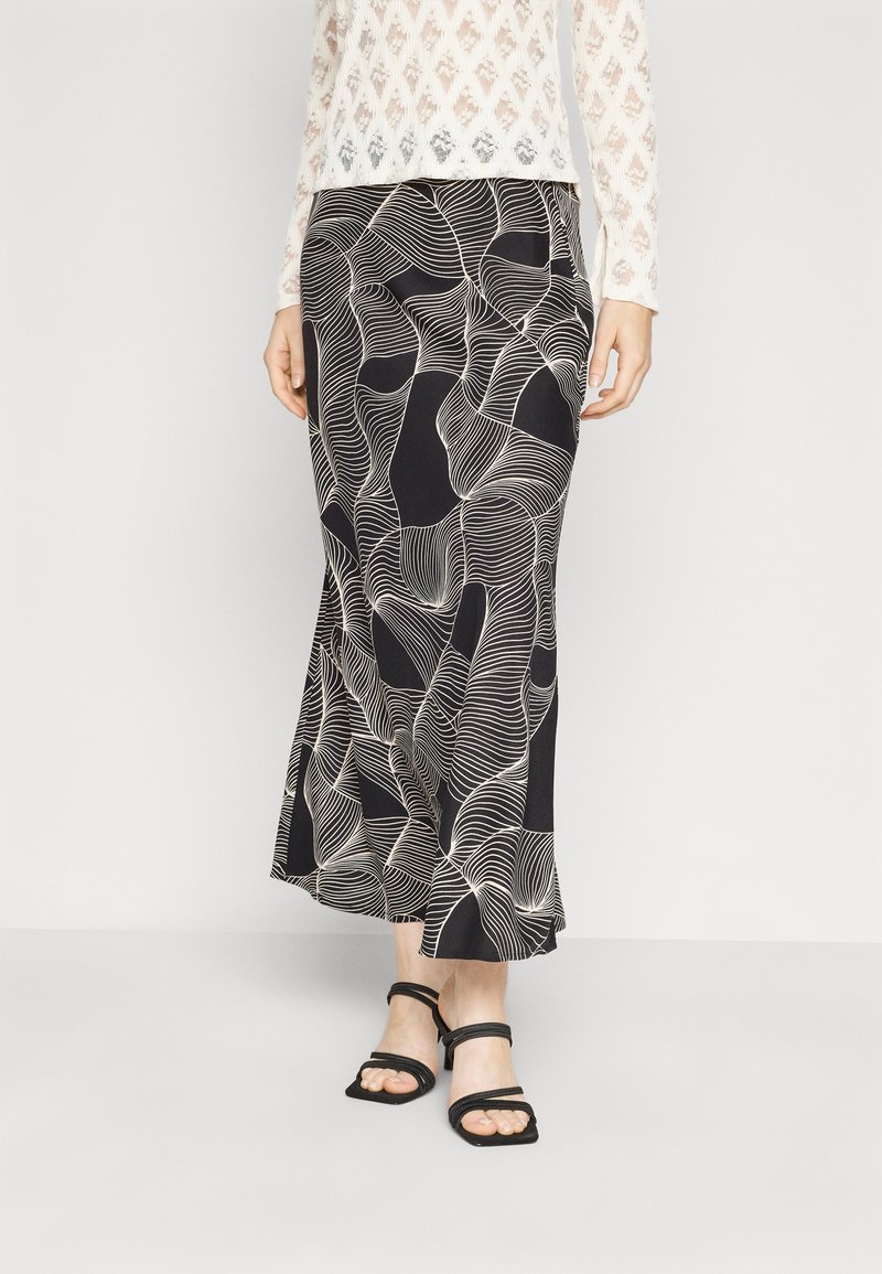 Gonna maxi nera con motivi ondulati bianchi; tessuto morbido che si adagia dolcemente. Abbinata a sandali neri con strap.
