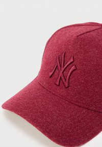 Gorra de béisbol de fieltro rojo con un logo bordado en la parte frontal, visera redondeada y tela texturizada, con detalles de costuras sin costuras.