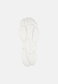 Suola di sneaker bianca con superficie in gomma texturizzata e sezioni arrotondate. Caratterizzata dalla sua costruzione leggera e design ergonomico.