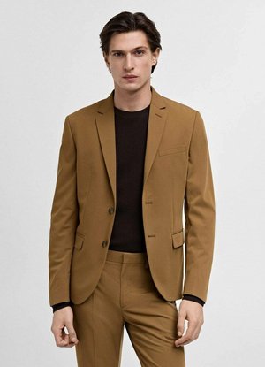 Brauner maßgeschneiderter Anzug mit einem einreihigen Blazer und einer schmal geschnittenen Hose, ausgestattet mit Reverskragen und einer Brusttasche, über einem dunkel gerippten Pullover.