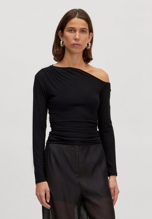 Zwarte one-shoulder lange mouw top van aansluitend, geribbeld materiaal. Heeft een gegatherde textuur op de schouder en een gladde silhouet.