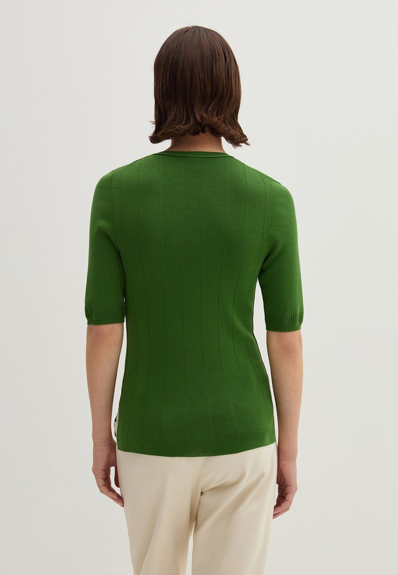 Maglione verde a coste con maniche corte e scollatura rotonda, dalla silhouette aderente. Presenta linee verticali e una finitura leggermente texturizzata.